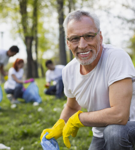 Experienced senior volunteer holding garbage bag