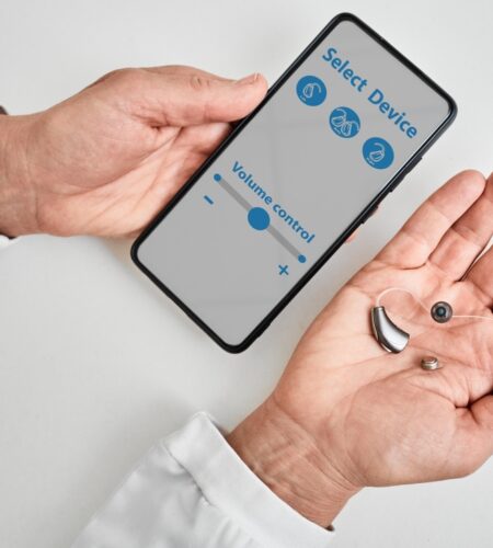 Doctor audiologist showing smartphone app for adjusting hearing